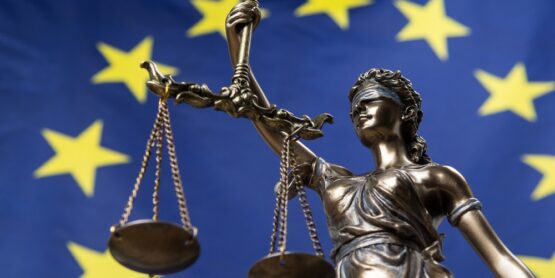 Estatua de la diosa de la justicia vendada, Themis o Justicia, frente a una bandera europea, como un concepto legal.